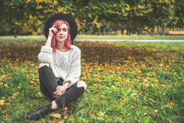 Pretty girl with red hair and hat relaxing in the park, autumn time.