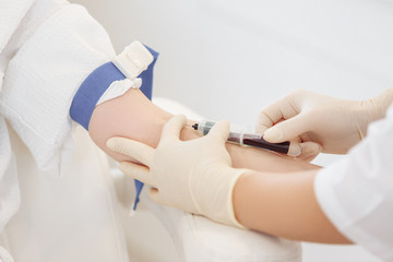 Doctor's hands take blood from a vein from a patient sitting in a chair. Blood test concept and detection of diseases