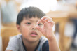 Close up an Asian boy' fingers holding his nasal mucus from nose.