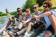 © Syda Productions - leisure, picnic and technology concept - friends with drinks taking picture by selfie stick on lake pier in summer park