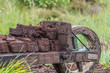 Pile of peat bog turf stacked up on a wooden wheelbarrow at a field in wiesmoor, germany.