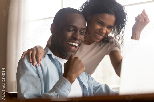 Fotografía African couple look at computer feels excited celebrating lottery win