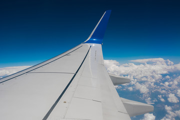 Airplane wing on blue sky and clouds background