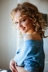 Close up portrait of blonde charming young woman with curly hair and natural makeup. Sunny morning, spa and care