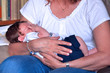 una donna tiene affettuosamente in braccio un neonato che dorme
