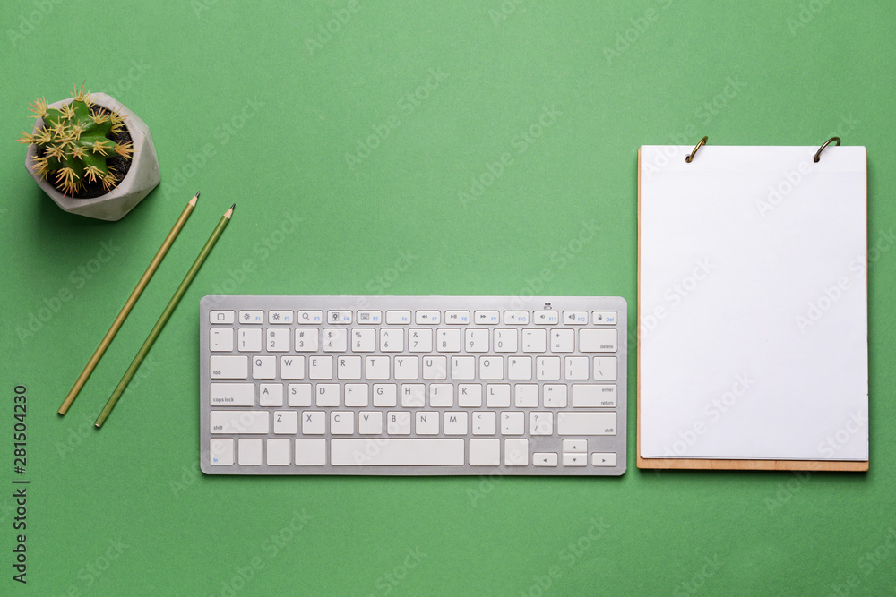 Modern computer keyboard with stationery on color background