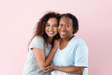 Portrait Of African-American Woman With Her Daughter On Color Background