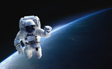 Fototapete - Astronaut in the outer space over the planet Earth. Abstract wallpaper. Spaceman. Black bakground. Elements of this image furnished by NASA