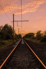 Canvas Print - Vertical shot of a railroad and wires with a beautiful pink sky and white clouds at dawn