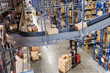 © Mint Images - View of conveyor belt, racks and forklift trucks in distribution warehouse