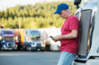 © Mint Images - Man using smartphone while leaning on truck grille at truck stop