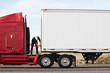 © Mint Images - Man connecting power cables to cab and trailer