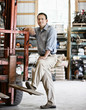© Mint Images - Portrait of man standing by forklift truck in equipment room