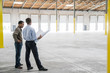 © Mint Images - Owner and architect talking over blueprints in warehouse