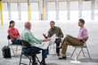 © Mint Images - Architects talking over blueprint while sitting in warehouse