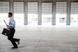 © Mint Images - Side view of architect with briefcase and blueprint running in warehouse