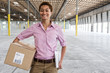 © Mint Images - Portrait of woman holding cardboard box in warehouse