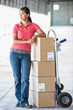 © Mint Images - Woman standing with hand truck in warehouse
