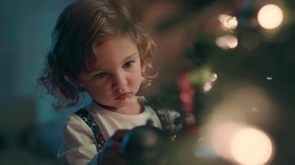happy little girl decorating christmas tree with beautiful ornaments and baubles enjoying festive de