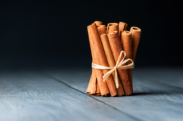 bunch of tied cinnamon sticks on black grey wooden rustic table, healthy spice concept