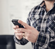 © Mint Images - Close up of businessman using smartphone in office