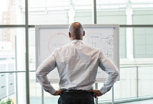 Rear View Of Businessman Looking At Whiteboard In Office