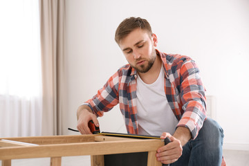 Sticker - Young working man using measure tape at home, space for text