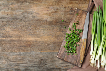 Flat lay composition with fresh green onions on wooden background. Space for text