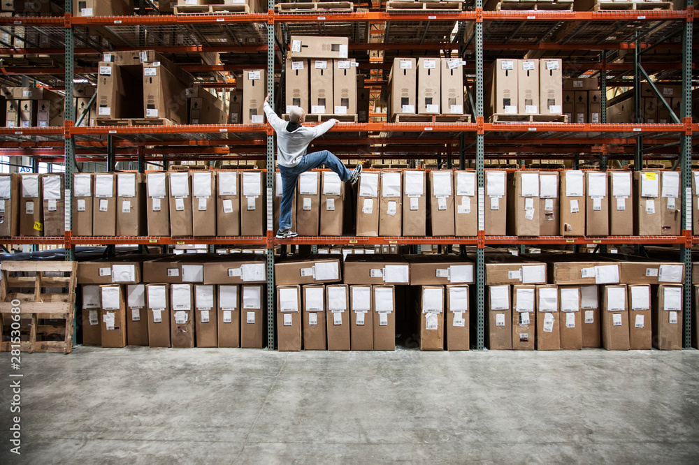 Worker trying to climb rack of products in warehouse Stock Photo ...