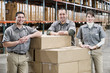 © Mint Images - Portrait of smiling workers with stack of boxes standing in warehouse