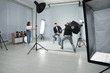 © New Africa - Professional photographer with assistant taking picture of young man in modern studio