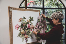 Senior Woman Comparing Fabric Pattern With Painting