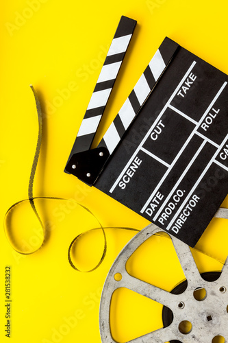 Go to the cinema with film type and clapperboard on yellow background top view