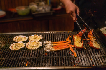 Wall Mural - Close up of hand grilling seafood on barbecue pan