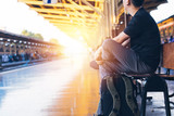 Fototapeta Uliczki - Young Asian male travel backpacker sitting and waiting for a train in railway platform in Bangkok, Thailand - Asia Travel tourism concept