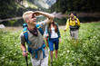 © NDABCREATIVITY - Group of happy friends with backpacks hiking together
