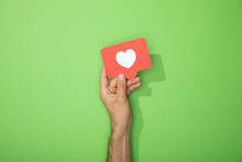 Cropped View Of Man Holding Red Paper Icon With White Heart On Green