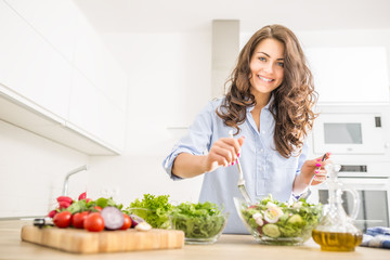 young woman preparing vegetable salad in her kitchen. healthy lifestyle concept beautiful woman with