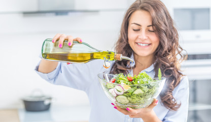 Wall Mural - Young woman pouring olive oil in to the salad. Healthy lifestyle eating concept