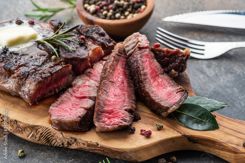 Cuadros en Lienzo Medium rare Ribeye steak with herbs and a piece of butter on the wooden tray
