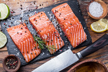 Wall Mural - Fresh salmon fillets on black cutting board with herbs and spices.