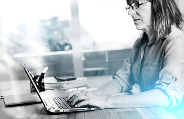 Wall Mural - Portrait of mature businesswoman using a laptop; light effect