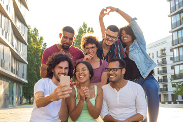 Excited overjoyed multiethnic people taking group selfie outside. Mix raced team of friends posing and laughing at phone camera. Group selfie concept