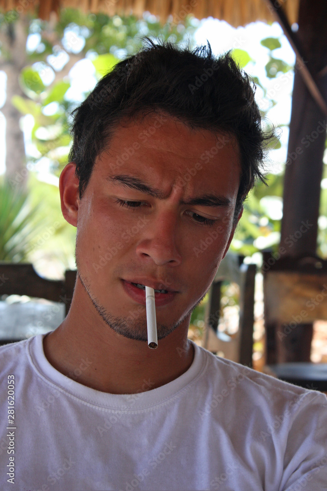 Young man looking concentrated with an unlit cigarette in his mouth Stock  Photo