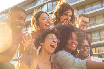 joyful multiethnic friends taking funny group selfie outside. mix raced men and women posing, grimac