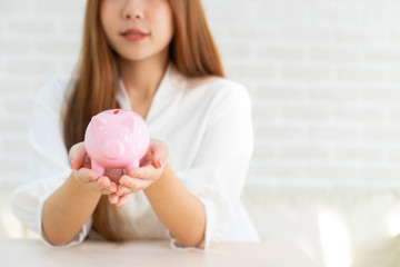 hand putting coin money to piggy bank saving, Close up of woman smiling putting a coin inside piggy bank as investment