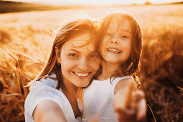 Wall Mural - close up portrait of a young beautiful mother embracing her daughter and looking at camera laughing 