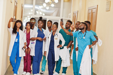 Wall Mural - Group of african medical students in college making selfie together on phone.