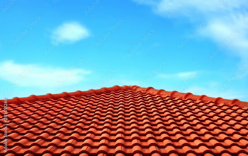 The old orange tiles roof slope in pyramid shaped against white clouds and blue sky 