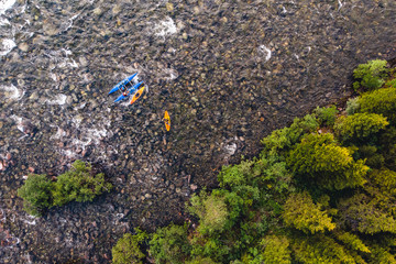 Wall Mural - Extreme sportsmen are kayaking and rafting on mountain river in forest. Aerial top view